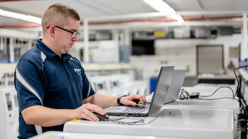 whypartner-hero Alliance Laundry Systems employee working on laptop in laundry facility
